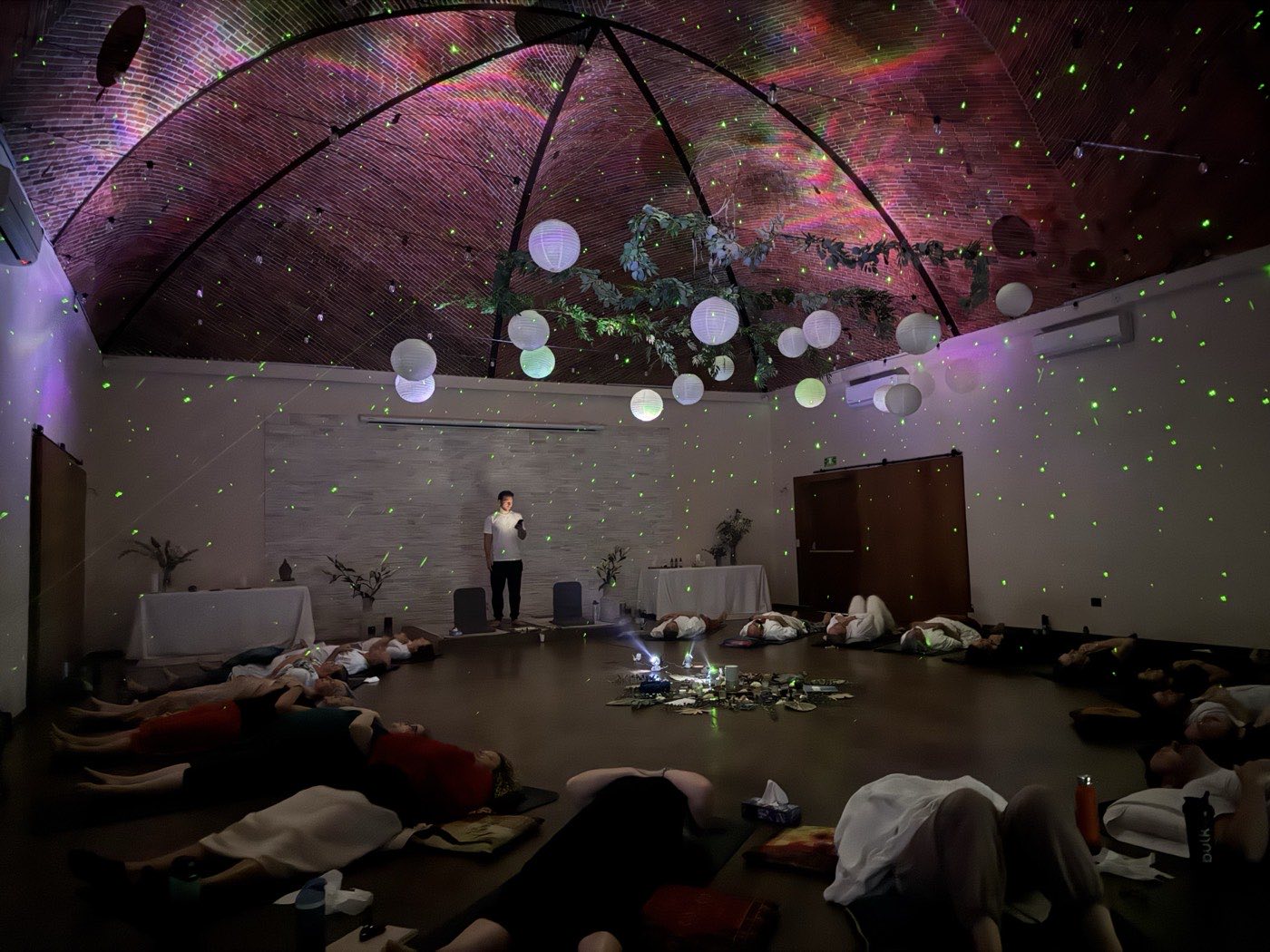 Wide purple-lit room, participants lying down