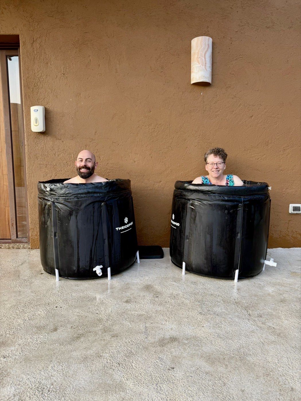 Two smiling guests in cold plunge tubs