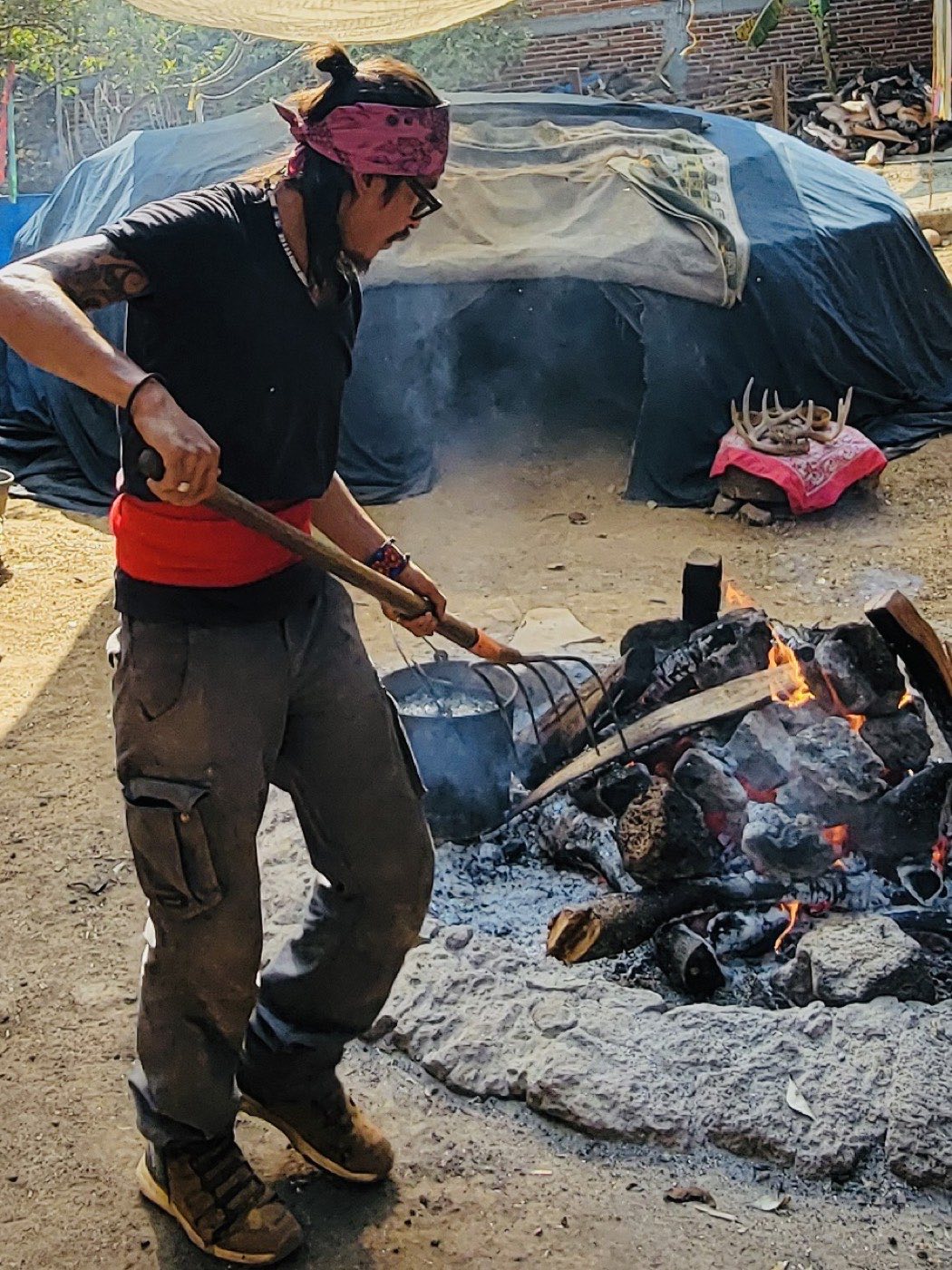 Firekeeper tending the fire beside the temazcal