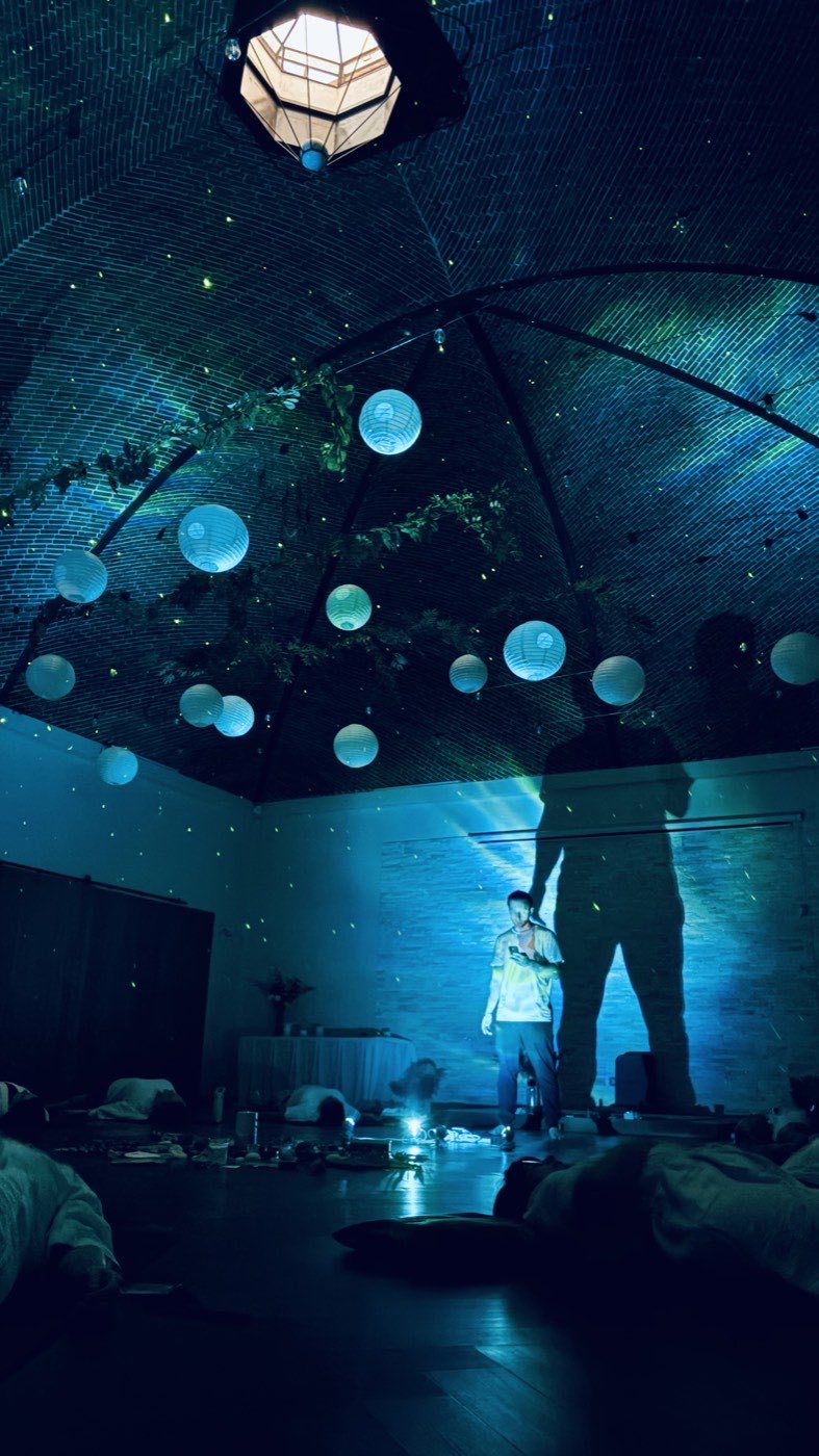 Blue-lit room, standing facilitator and large shadow