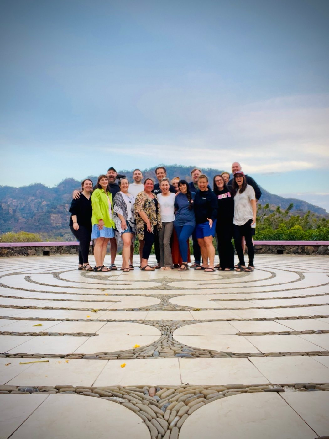 A group from one of Jacob’s in-person retreats, standing on a stone labyrinth with mountains behind